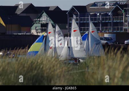 Yacht retroilluminato vele dietro la duna di sabbia Marram erba. Exmouth da Dawlish Warren, Devon, Regno Unito. Luglio, 2017. Foto Stock