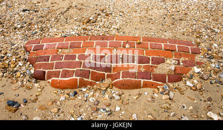 Muro di mattoni che giace nella sabbia Foto Stock