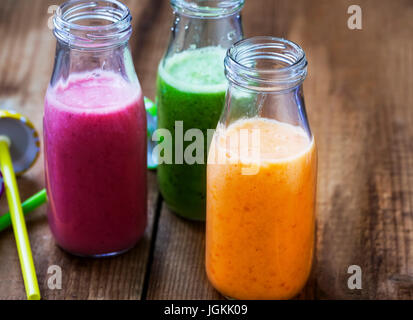 Freschi frullati in bottiglie in tre colori: verde con spinaci e kiwi, rosa con fragole, arancione con albicocche, sana detox frullati Foto Stock