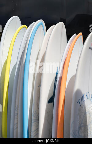 Display in rack di tavole da surf per il noleggio e la vendita alla cittadina di mare, Newquay Cornwall - Home di Boardmasters Festival. Foto Stock