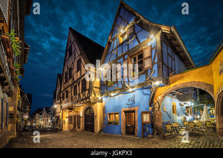 I tradizionali colorati a struttura mista in legno e muratura case francesi sulla via centrale del villaggio di Riquewihr in serata, Alsazia, Francia Foto Stock