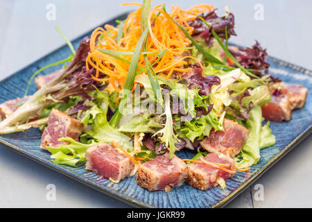 Disseccata ahi tonno servita con verdure miste, le carote grattugiate e le cipolle verdi Foto Stock