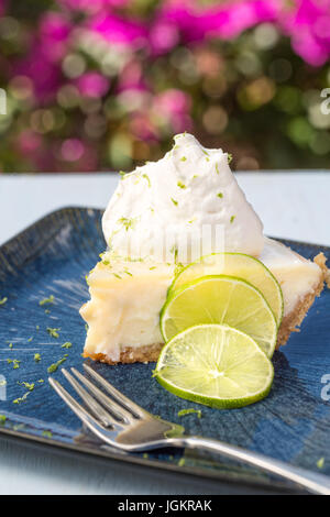 Una fetta di key lime pie servita con la panna montata e la scorza del lime Foto Stock