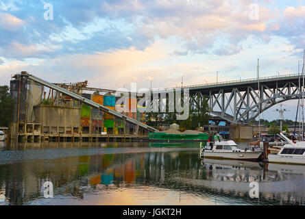 Una vista su Granville Island con il resto del paesaggio industriale, ormeggiate barche e Granville Street Bridge attraverso False Creek. Foto Stock