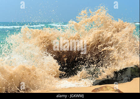 Onda alta la rottura sulle rocce della costa Foto Stock