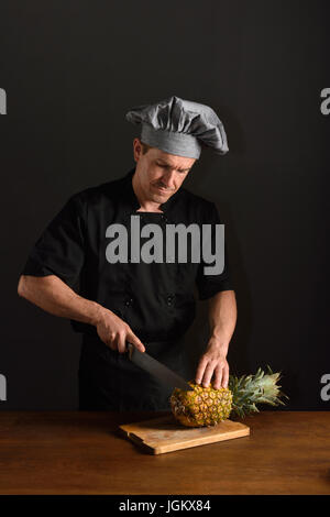 Lo chef il taglio di un ananas Foto Stock