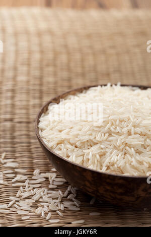 Riso Basmati nella ciotola di legno su sfondo di paglia Foto Stock