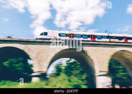 Ginevra, Svizzera - 25 Giugno 2017: Swiss treno regionale che passa al di sopra di un ponte nel Cantone di Ginevra regione, con motion blur. Foto Stock