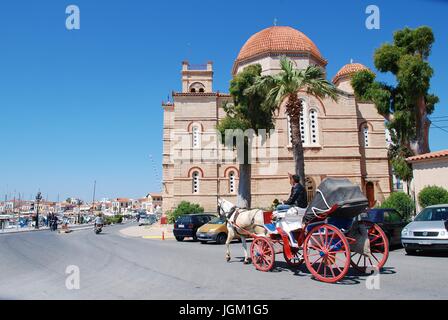Un cavallo e carrozza dando giostre per turisti passa la chiesa del Panagitsa a Aegina città sull'isola greca di Egina il 26 aprile 2017. Foto Stock