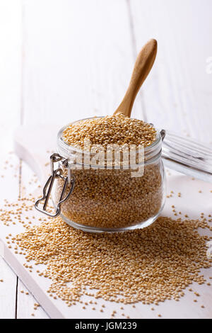 Quinoa bianco semi in un vaso su bianco tavolo in legno, primo piano Foto Stock