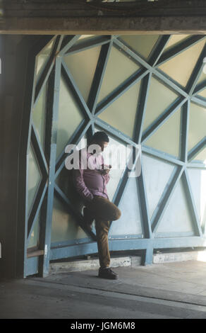 Giovane uomo attende una metropolitana trtain sulla piattaforma sopraelevata a W. 8th Street a Coney Island, Brooklyn, New York. Foto Stock