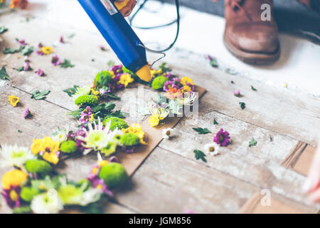 Fioraio effettuare decorazioni di fiori con lettere e colla. In interni luce naturale shot con piccole profondità di campo Foto Stock