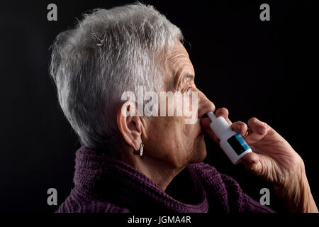 Vecchia donna con spray nasale Foto Stock