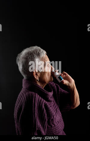 Vecchia donna con spray nasale Foto Stock