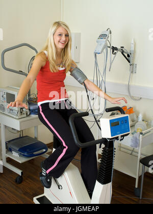 Giovane donna svolge un ergometro test nella pratica medica - una giovane donna su un ergometro in chirurgia, Junge Frau führt einen Ergometer-Test Foto Stock