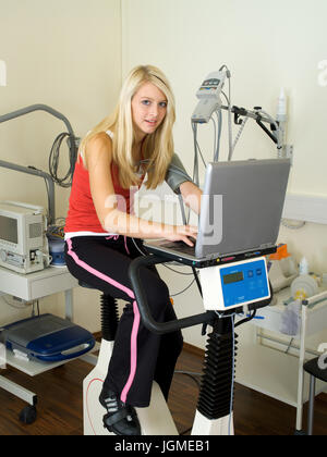 Giovane donna svolge un ergometro test nella pratica medica - una giovane donna su un ergometro in chirurgia, Junge Frau führt einen Ergometer-Test Foto Stock