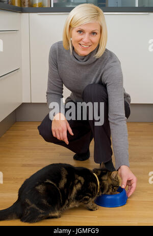 Donna alimenta il gatto - Donna alimentazione del gatto, Frau füttert die Katze - Donna alimentazione del gatto Foto Stock