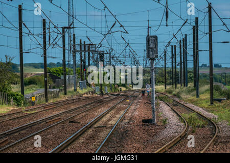 Parallelamente i binari ferroviari con taglio curvo, segnali e cavi aerei, Drem stazione ferroviaria, East Lothian, Scozia, Regno Unito Foto Stock