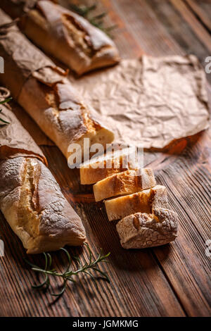 Fresca baguette francese su una tavola di legno avvolti in carta kraft Foto Stock