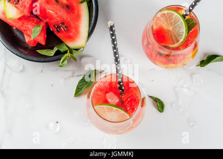 Estate cocktail e bevande. La limonata, in casa di sangria con fresco cocomero, lime, menta e ananas. In due bicchieri, su un marmo bianco tavola. Cop Foto Stock