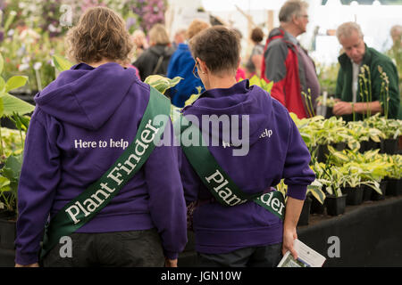 2 volontari di sesso femminile, lavorando come cercatori di piante, di stare in piedi insieme guardando le piante - marquee, RHS Chatsworth Flower Show showground, Derbyshire, GB, UK. Foto Stock