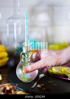 Il design piccolo vaso con paglia riempito con acqua di infuso di limone, la paglia. Fresche, estate umore. Foto Stock