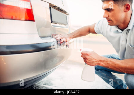 Automobile lucidatura sul car wash stazione. Uomo di sfregamento del paraurti del veicolo con il polacco. Foto Stock