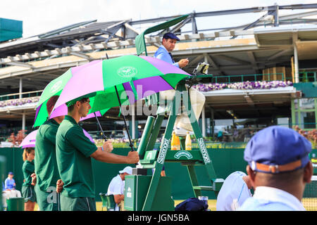 Corte di Wimbledon famigli tenere ombrelli per ombreggiare i giocatori dal sole su un insolitamente calda e soleggiata giornata a Wimbledon Tennis Championships 201 Foto Stock