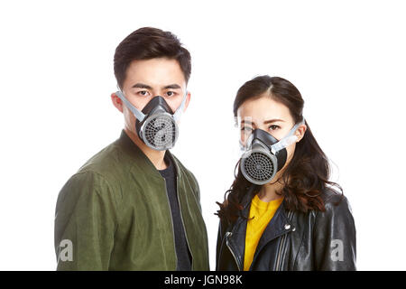 Giovani asiatici giovane indossando maschera a gas fissando fotocamera, isolati su sfondo bianco. Foto Stock