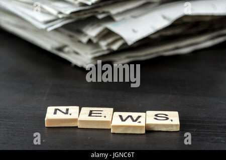 Close up di piastrelle di legno l'ortografia della parola news di fronte quotidiani Foto Stock