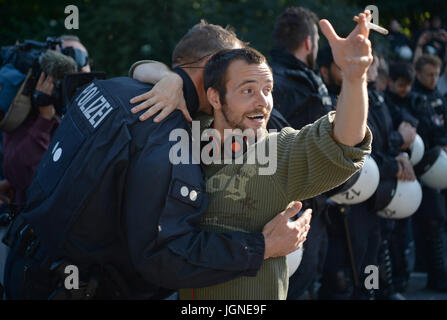 Amburgo, Germania. 8 Luglio, 2017. Un dimostrante e un poliziotto abbraccio durante una dimostrazione in piazza Millerntor ad Amburgo, Germania, 8 luglio 2017. La due giorni del Vertice, una riunione dei leader dei venti maggiori economie del mondo così come i rappresentanti di una vasta gamma di istituzioni internazionali, si conclude oggi. Foto: Christophe Gateau/dpa/Alamy Live News Foto Stock