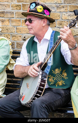 Uomo caucasico, 40s, folk musicista banjo dal Maldon Greenjackets Morris lato. Seduto con banjo nel suo giro. Foto Stock