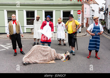 Il Upcross Mummers esecuzione tradizionale gioco mumming dal medioevo circa l uccisione di un agnello dal macellaio locale. Gli attori in vari costumi intorno permanente di ovini macellati in strada al panino città durante il Folk e Ale festival. Foto Stock