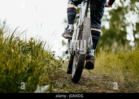 Primo piano Il fango mountain bike ruota e gambe del ciclista Foto Stock