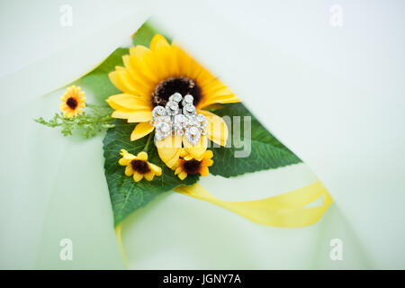 Le donne di nozze da Orecchini oro bianco e diamanti closeup su sfondo di girasole. sposa accessori. Foto Stock