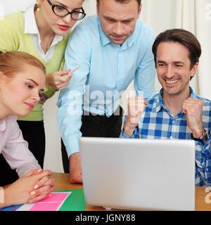 Team aziende lavorano insieme guardando un portatile al lavoro Foto Stock
