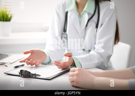 Close up il medico e il paziente seduto alla scrivania vicino alla finestra in ospedale Foto Stock