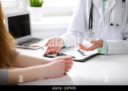 Close up il medico e il paziente seduto alla scrivania vicino alla finestra in ospedale Foto Stock