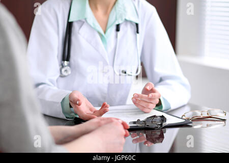 Close up il medico e il paziente seduto alla scrivania vicino alla finestra in ospedale Foto Stock