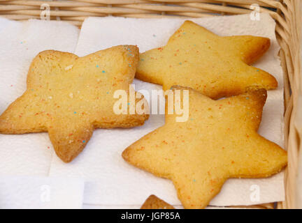 Tre stelle di zucchero a forma di cookie con spruzzi di arcobaleno in un cesto di vimini Foto Stock