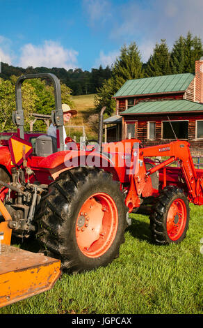 20's donna agricoltore sul trattore rosso, agriturismo in background Foto Stock