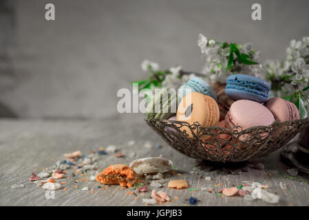 Amaretti multicolore su una tabella con vaso orientale e il ramo di ciliegio in fiore Foto Stock