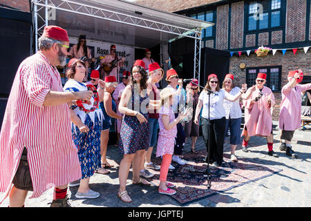 Gruppo di musica la favolosa Fezheads eseguendo nella piazza del paese a sandwich in caso durante il Folk e Ale festival. I membri del pubblico e il gruppo nella parte anteriore dello stadio ballare insieme durante un cantare insieme. Foto Stock