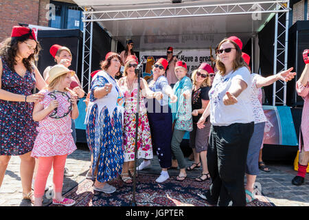 Gruppo di musica la favolosa Fezheads eseguendo nella piazza del paese a sandwich in caso durante il Folk e Ale festival. I membri del pubblico e il gruppo nella parte anteriore dello stadio ballare insieme durante un cantare insieme. Foto Stock