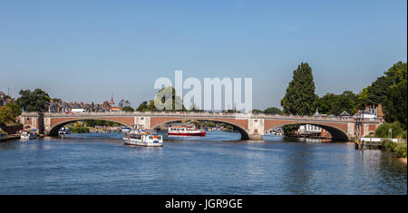 Hampton Court ponte (1933) oltre il Fiume Tamigi tra Hampton, a Londra e a East Molesey, Surrey con segnale di occupato traghetti e una coda di passeggeri. Foto Stock