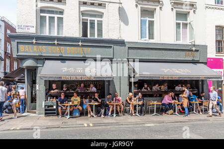 Ai clienti di rilassarsi, mangiare e bere fuori e dentro Balans Società Soho bar e brasserie in Old Compton Road, Soho, London, England, Regno Unito Foto Stock