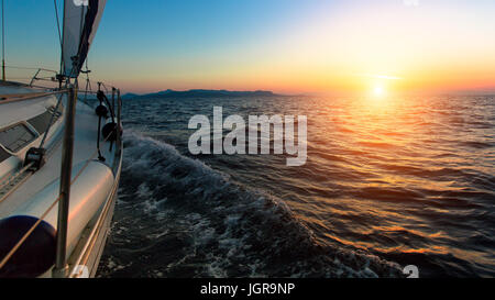 Tramonto dal ponte della barca a vela in movimento in un mare. Foto Stock