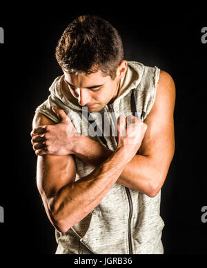 Montare giovane uomo flettendo il suo bicipite isolato su sfondo nero Foto Stock