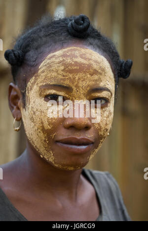 MADAGASCAR, Morondava - Agosto 8, 2011: Ritratto di giovane donna dal villaggio in una maschera di argilla su una faccia. Foto Stock