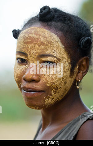 MADAGASCAR, Morondava - Agosto 8, 2011: Ritratto di giovane donna dal villaggio in una maschera di argilla su una faccia. Foto Stock